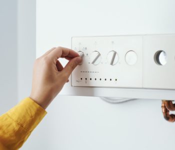 Young woman checking settings and temperature on the boiler at home