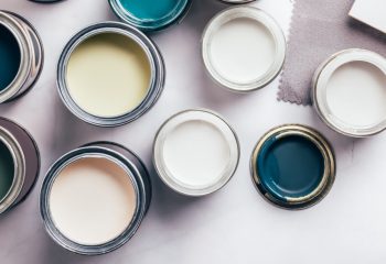 Tiny sample paint cans during house renovation, process of choosing paint for the walls, different green and beige colors, color charts on background, banner size